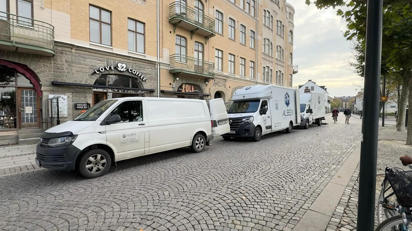 En flyttbil från Albex Moving parkerad vid Clemenstorget i Lund, nära Love Coffee & Wine Bar och Lunds centralstation, under ett pågående flyttuppdrag i stadens historiska kvarter.